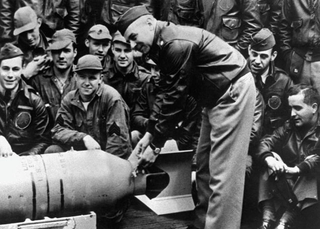 Lt. Col. Doolittle attaches Japanese friendship medals, awarded before the war, to a bomb that will be dropped on Japan while pilots and crewmen look on (US Navy)